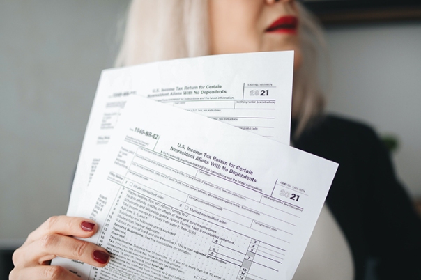 Woman holding up two tax forms in front of her face .